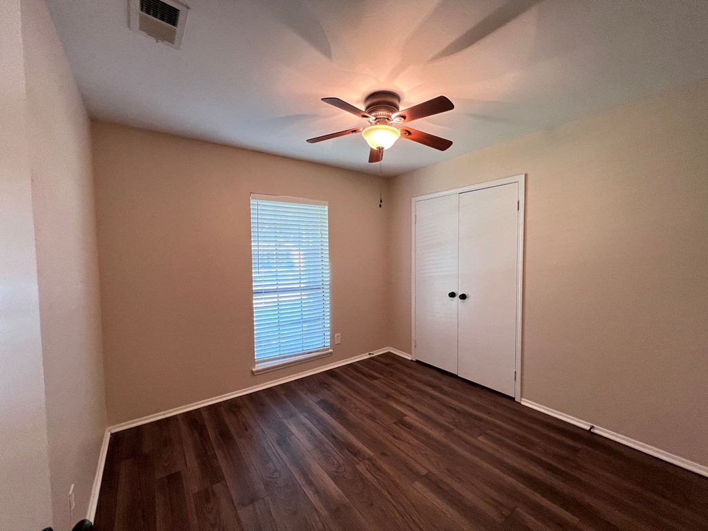 A room with a ceiling fan and a window with blinds.