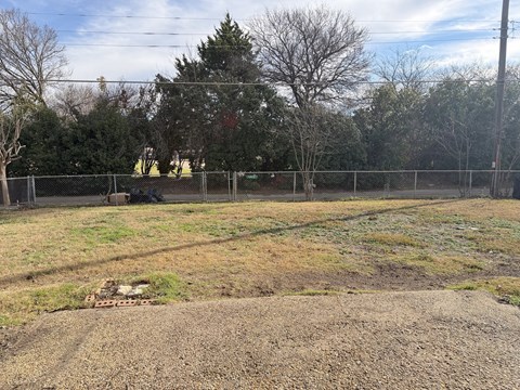 A field with a fence and trees in the background.