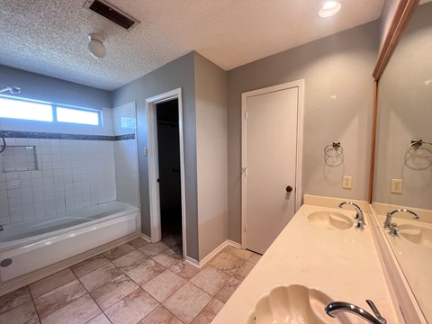A bathroom with a white bathtub, sink, and mirror.