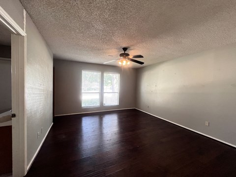 A room with a ceiling fan and sliding glass doors.