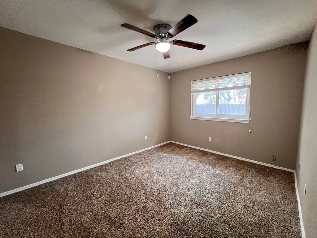 A room with a ceiling fan and carpeted floor.