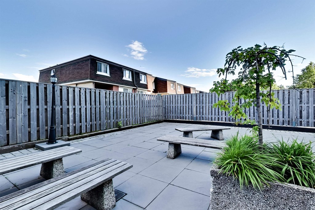 a patio with benches and a fence and some buildings