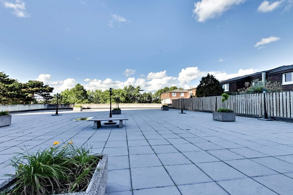 a large patio with a bench and a pool in the background