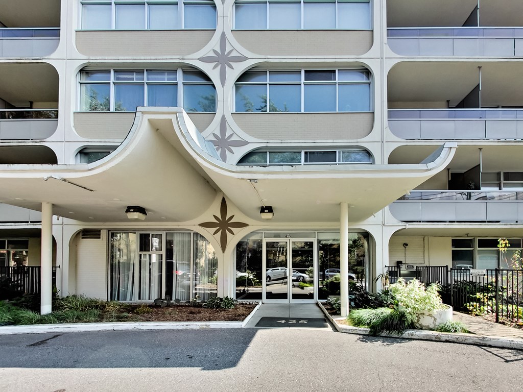 A modern building with a white facade and a large glass window.