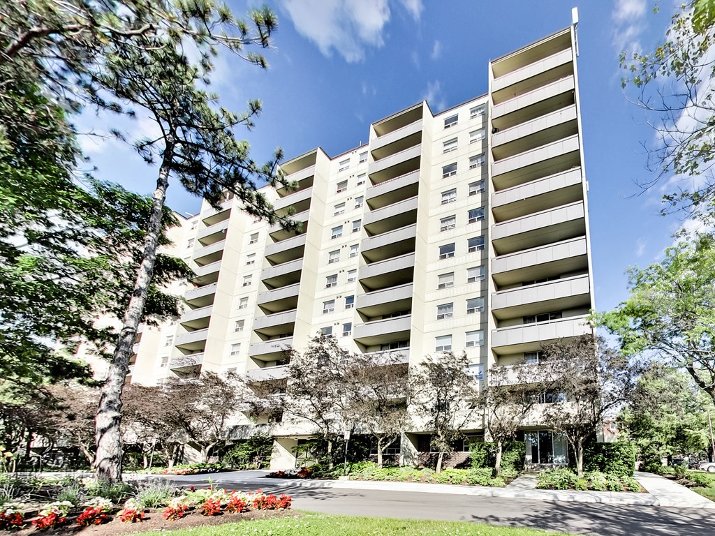 an apartment building with a sidewalk and trees in front of it