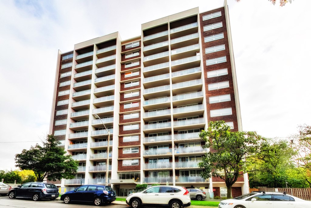 A large apartment building with cars parked in front.