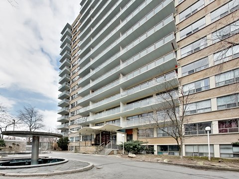 A tall residential building with a pool in front.