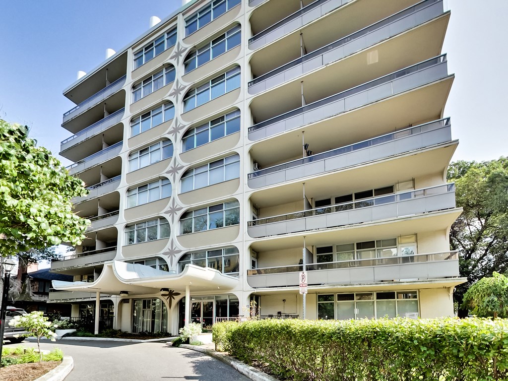 A large white apartment building with balconies and a covered walkway.