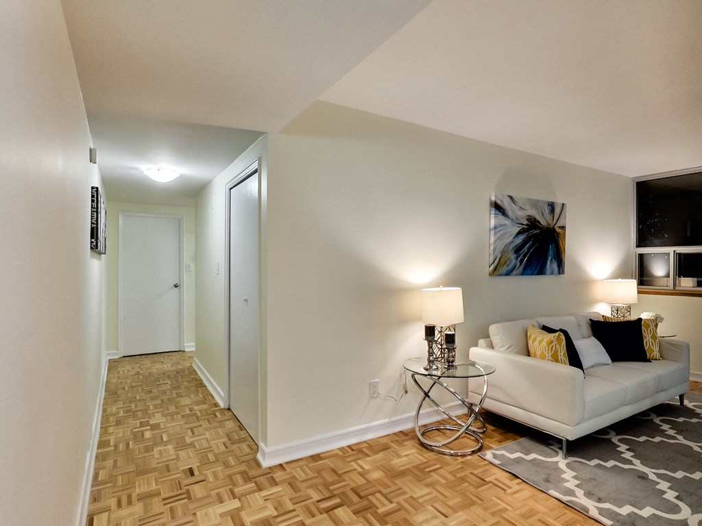 A living room with a white couch and a painting on the wall.
