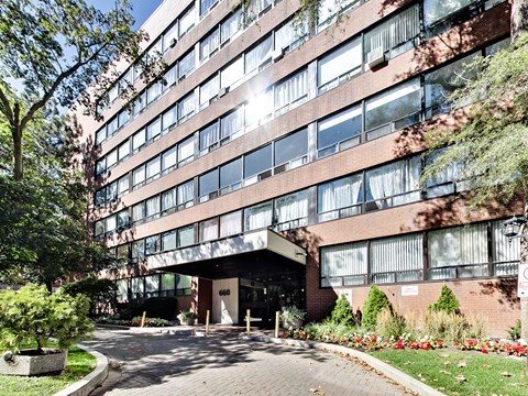 A large red brick building with a glass entrance and a tree in front.