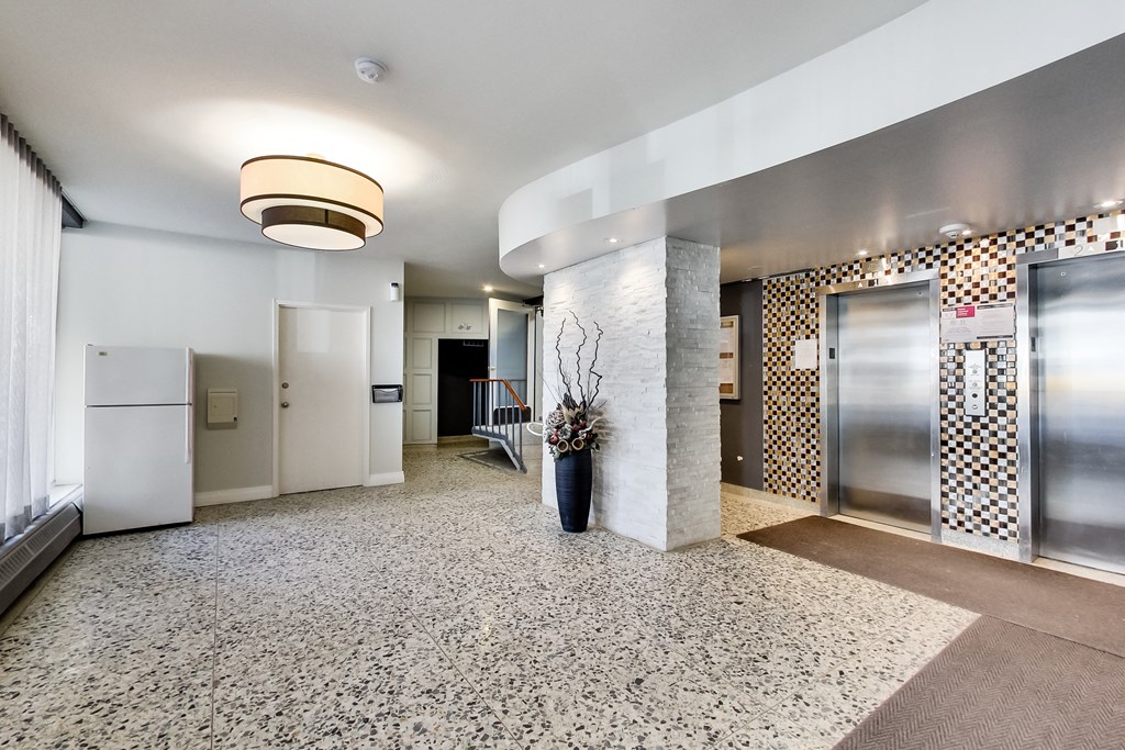 A white fridge is in a room with a tiled floor.