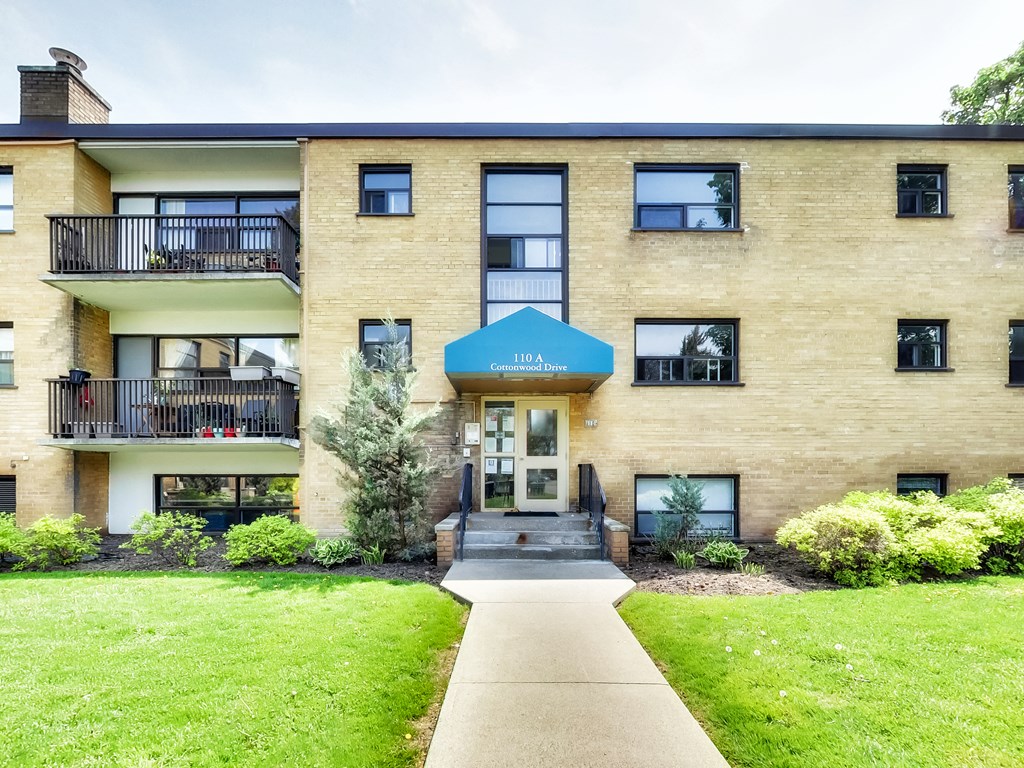 A building with a blue awning and a balcony with chairs and plants.