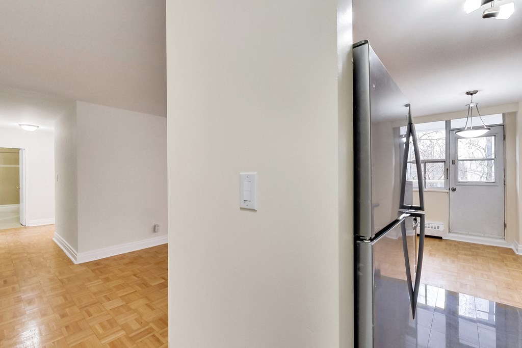 A kitchen with a refrigerator and a wooden floor.