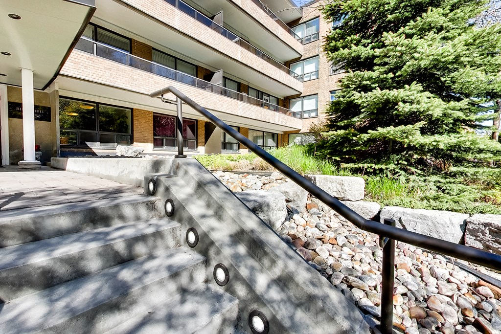 stairs leading up to an apartment building with rocks and trees