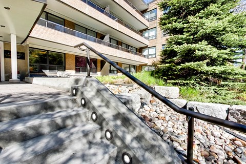 stairs leading up to an apartment building with rocks and trees