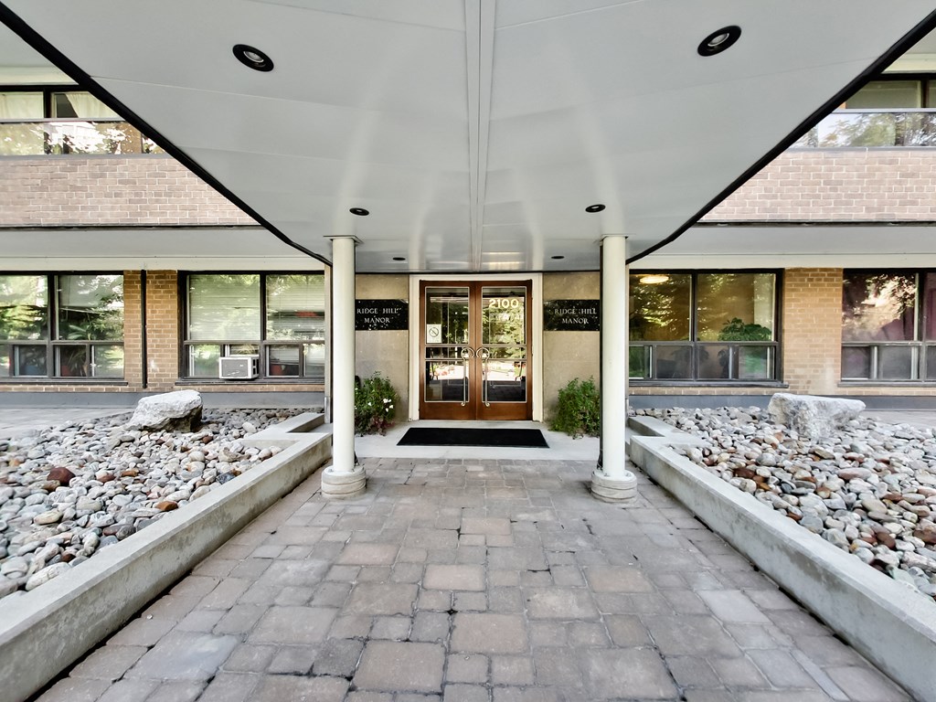 the front entrance of a building with a brick walkway and rocks