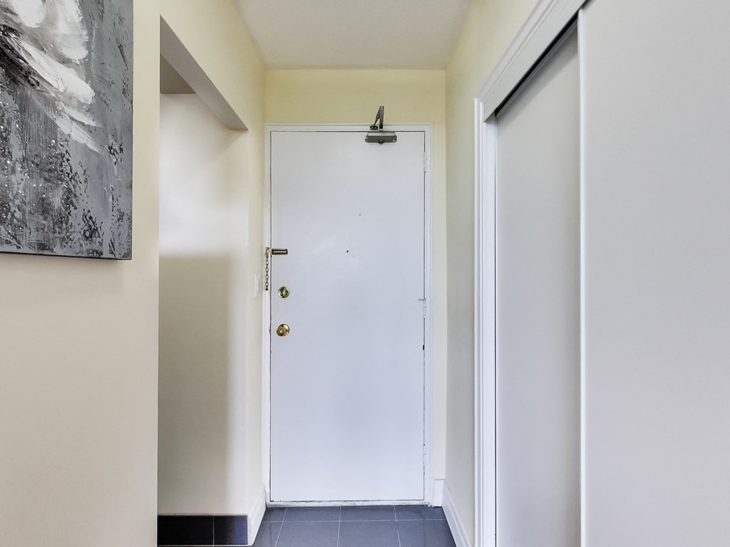 A white door with a black handle is in a hallway.