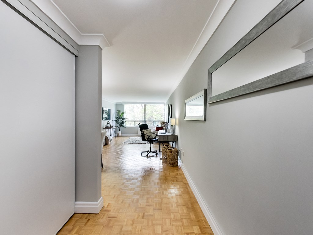 A long hallway with a chair and a mirror on the wall.