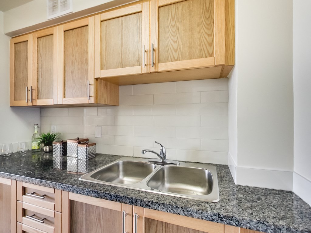 A kitchen with a granite countertop and wooden cabinets.