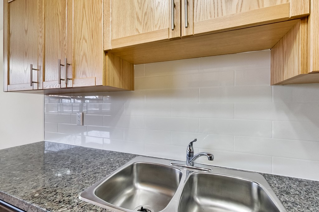 A kitchen with a granite countertop and a double sink.