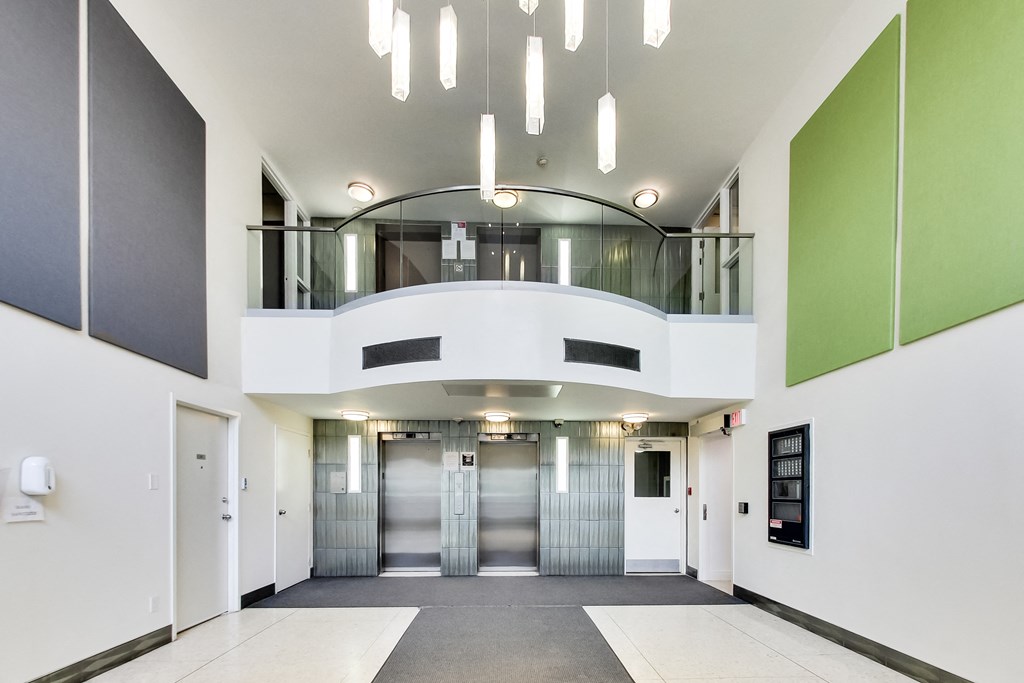 A hallway with a white floor, white walls, and a green accent wall.
