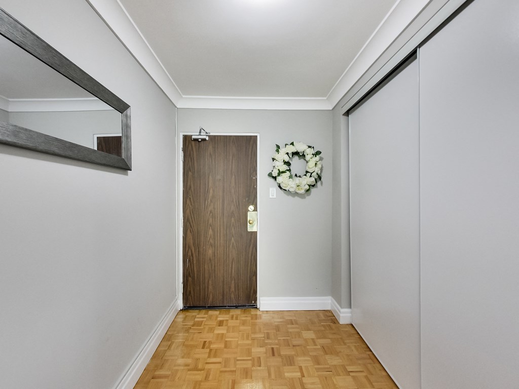 A hallway with a wooden door and a wreath on the wall.