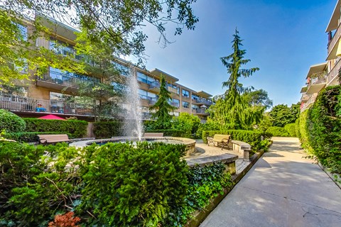a courtyard with a fountain and benches in front of an apartment building