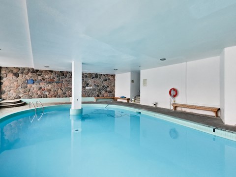 a swimming pool with blue water and a stone wall