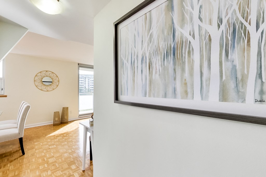 A painting of trees hangs on a wall above a table.