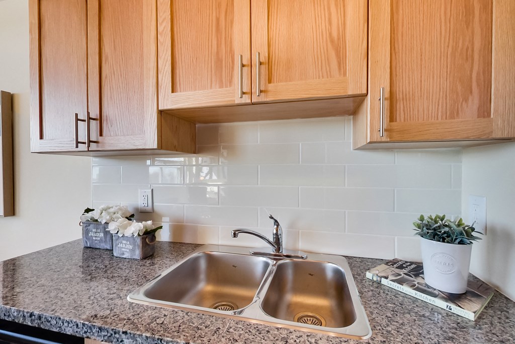 A kitchen with a double sink and wooden cabinets.
