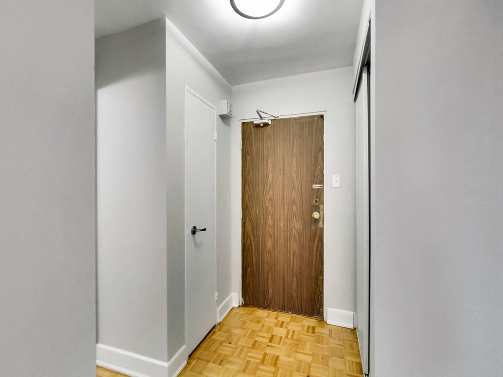 A hallway with a wooden door and a white wall.