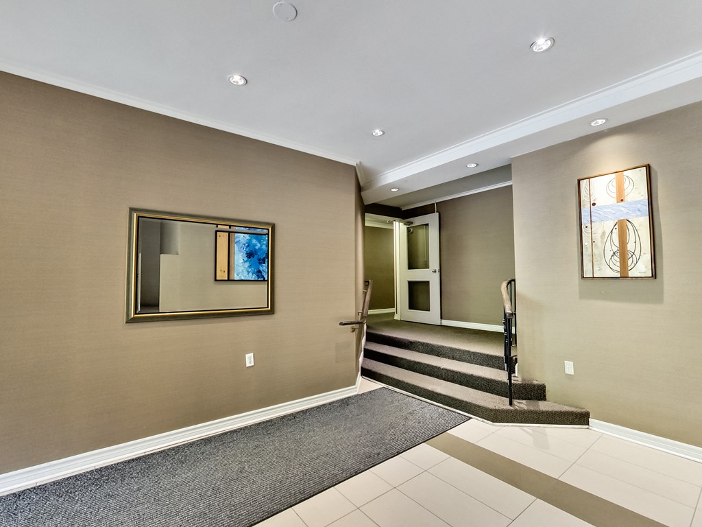 a entryway with carpet and stairs and a mirror on the wall