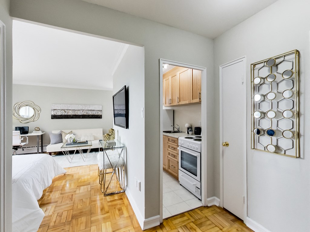 a bedroom with a bed and a living room with a desk and a kitchen