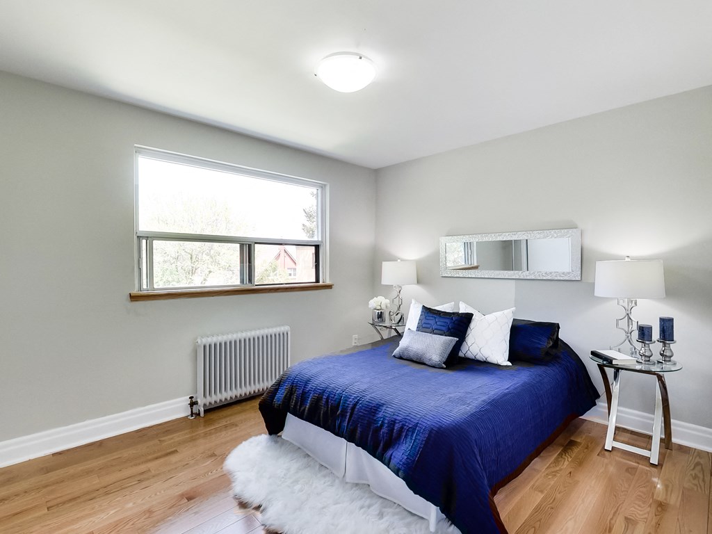 A bedroom with a blue bedspread and a white rug.