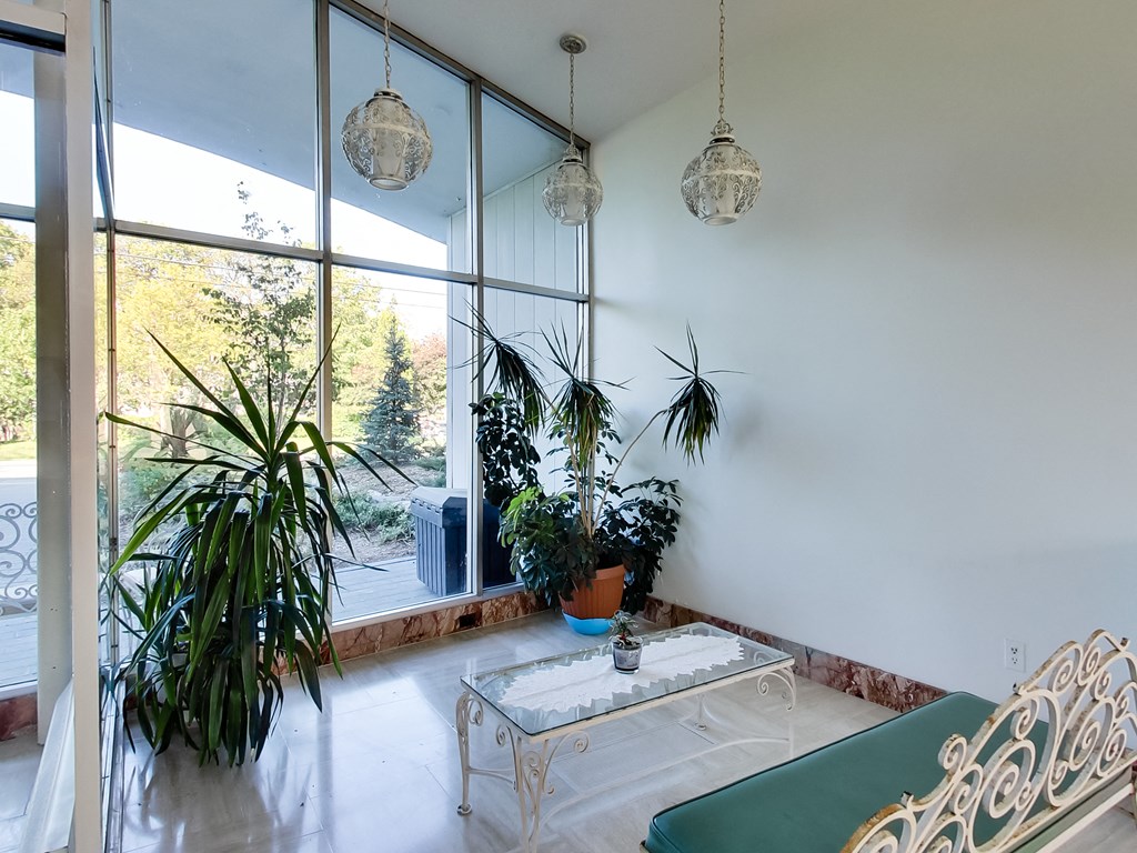 a living room with a large window and several potted plants