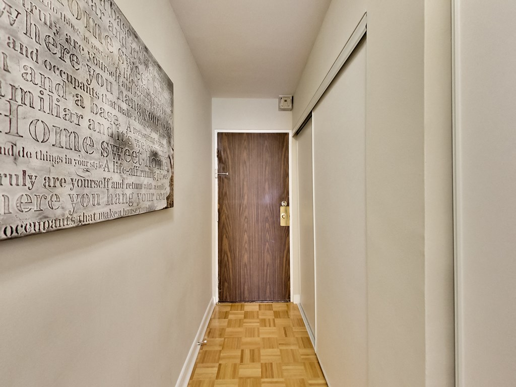 A hallway with a wooden floor and a wall with a word cloud on it.