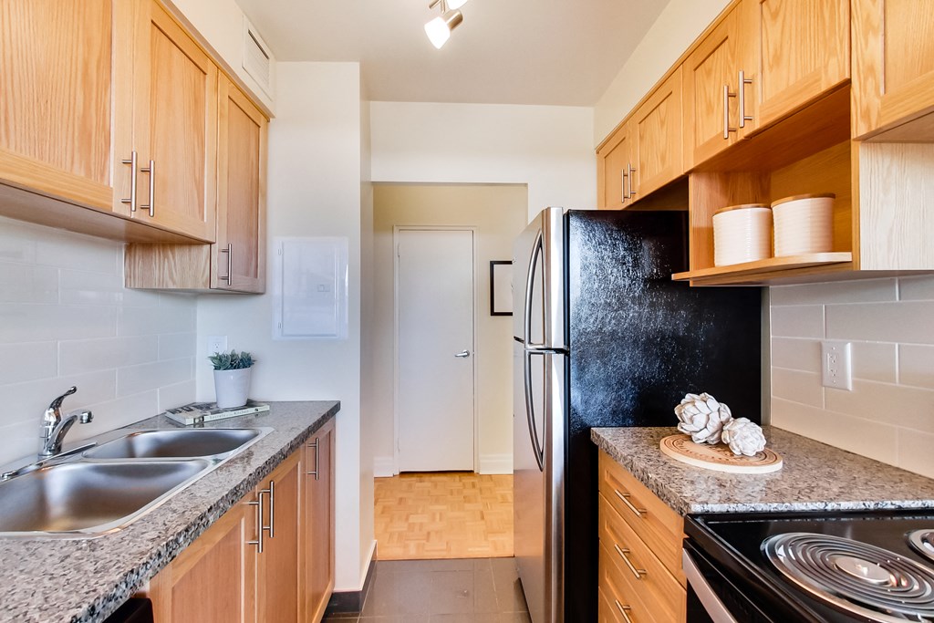 A kitchen with a black refrigerator and wooden cabinets.