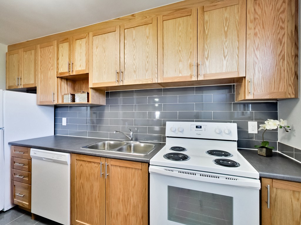 A kitchen with wooden cabinets and a white stove top oven.