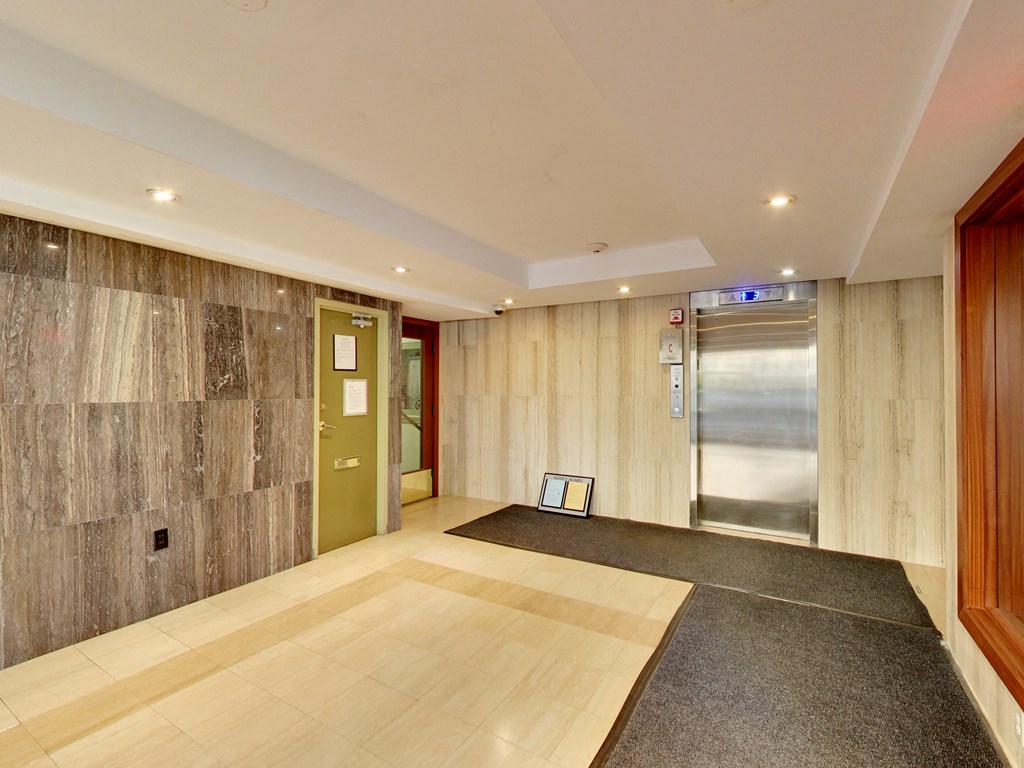 A hallway with a wooden floor and a grey carpet.