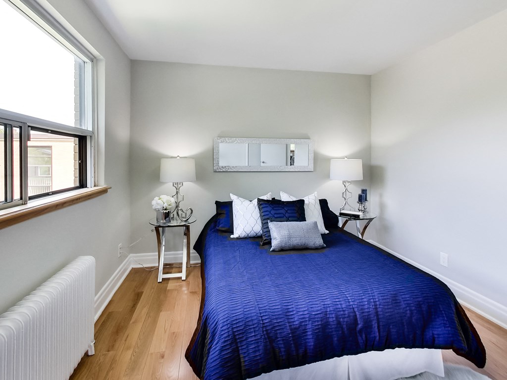 A bedroom with a blue bedspread and two white lamps.