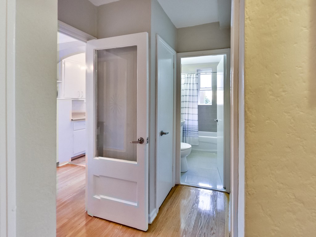 an open door leading into a bathroom with a toilet and a shower