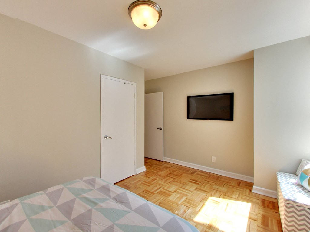a bedroom with a tv on the wall and a bed