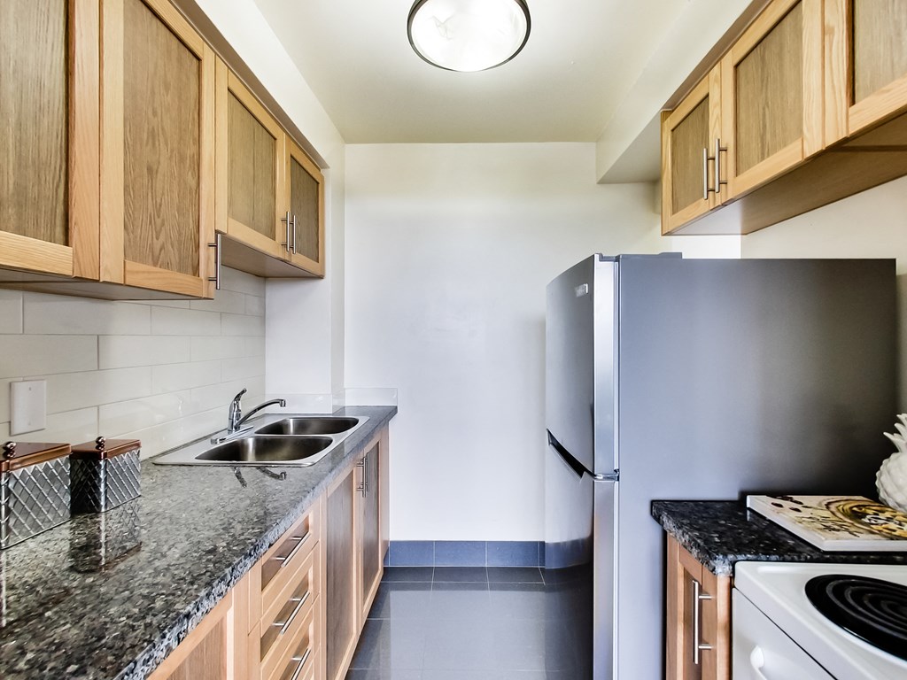 A kitchen with a black granite countertop and wooden cabinets.
