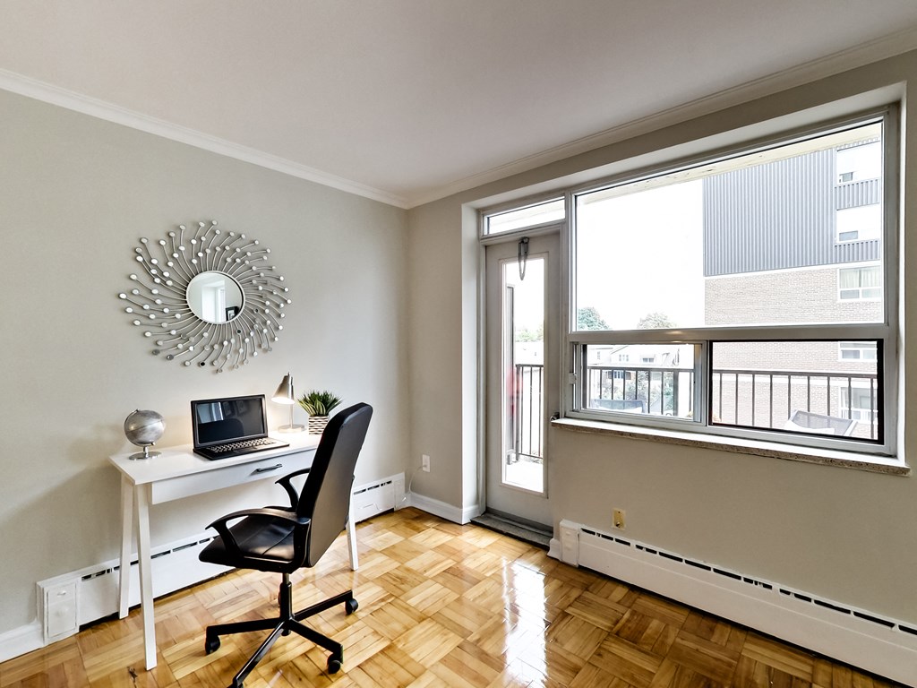 a home office with a desk and a laptop and a large window