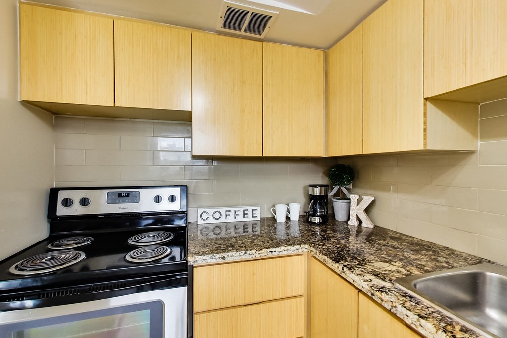 A kitchen with a stove, sink and counter.