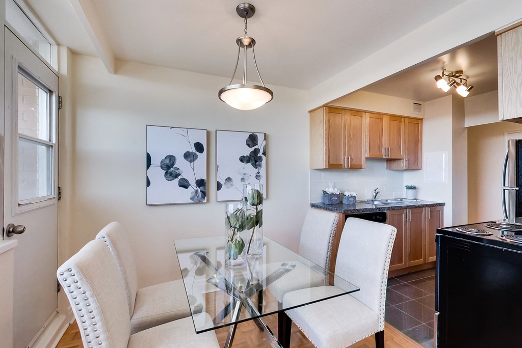 A modern kitchen with a glass table and white chairs.