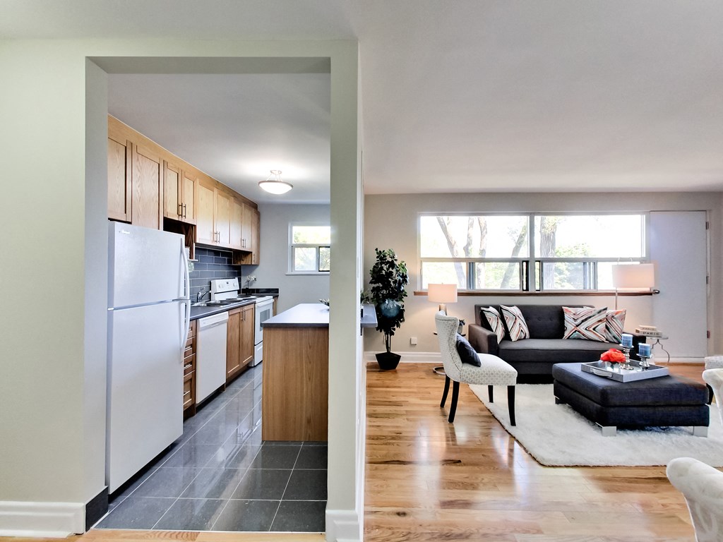 A modern kitchen and living room with wooden floors and furniture.