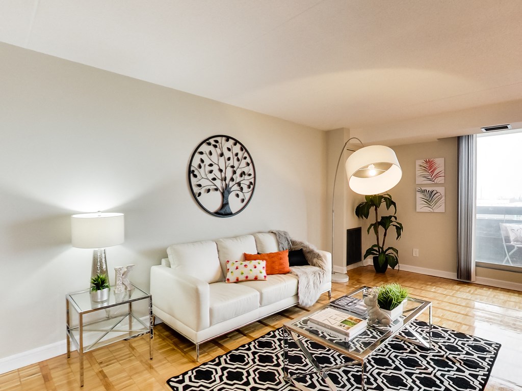 a living room with a white couch and a glass coffee table and a large window