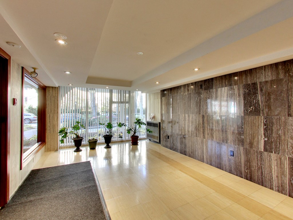 A hallway with a brown marble wall and a grey carpet.