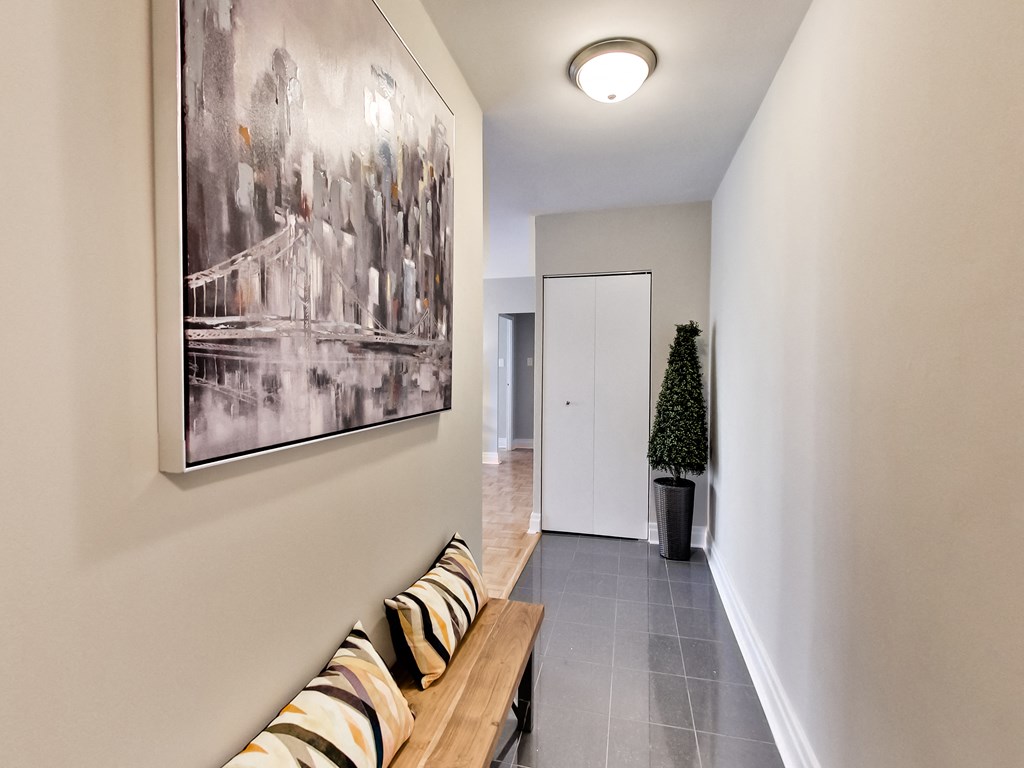 a hallway with a wooden bench and a painting on the wall